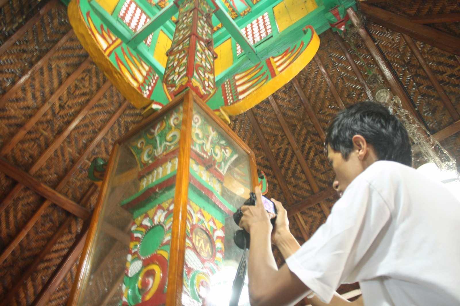 Seorang pengunjung memotret angka yang tertera pada tiang Masjid Saka Tunggal.