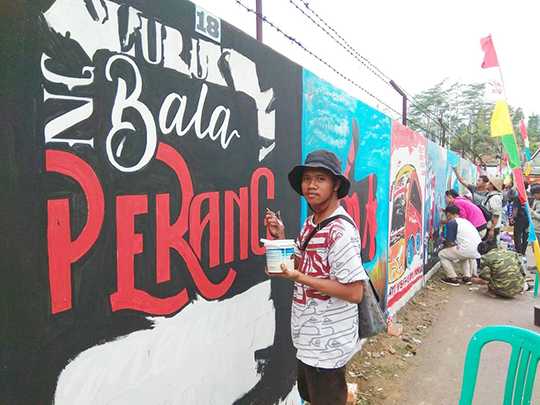 MELUKIS MURAL: Peserta menuangkan kreativitas tema dengan gambar mural di dinding tepi jalan dalam Lomba Mural di Kecamatan Karangkobar, Sabtu (31/8). (SB/Castro )