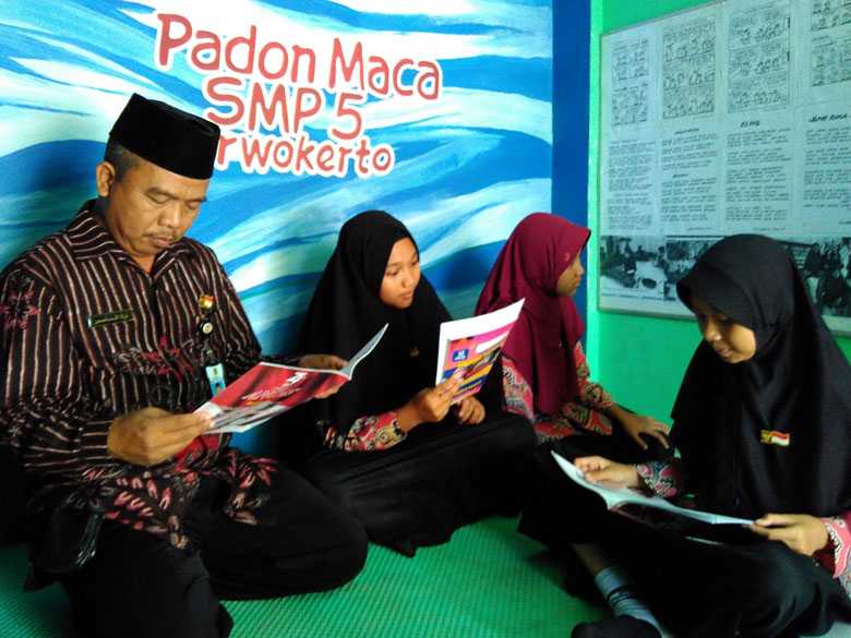 BACA BUKU: Siswa dan guru membaca buku berbahasa Banyumasan di perpustakaan mini SMP 5 Purwokerto, baru-baru ini.(SB/Budi)