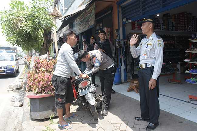 PENERTIBAN PARKIR: Petugas menertibkan kendaraan diparkir di trotoar Jalan Jendral Soedirman Purwokerto, Rabu (23/10)