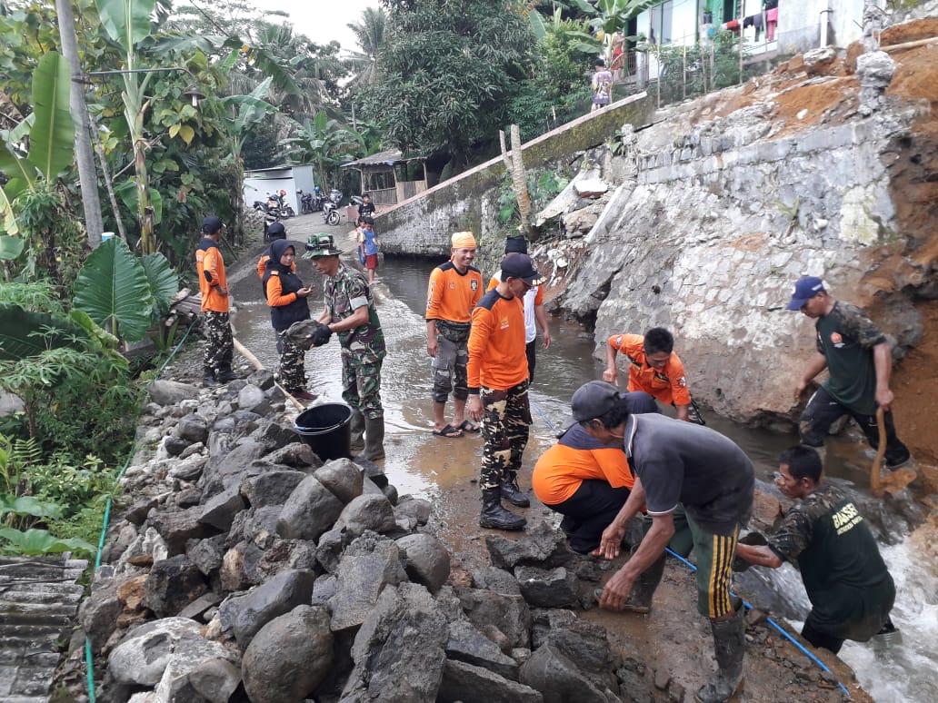 KERJA BAKTI: Masyarakat, TNI-Polri, Tagana, Bagana, BPBD Banyumas kerja bakti menyingkirkan puing tebing pengaman irigasi yang longsor Minggu (15/3).