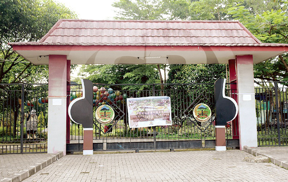 DITUTUP :Spanduk dipasang di gerbang Taman Andhang Pangrenan Purwokerto yang tertutup rapat, Senin (30/3). Sejumlah objek wisata ditutup sebagai upaya antisipasi penyebaran virus Covid-19.(SM/Dian Aprilianingrum-60)