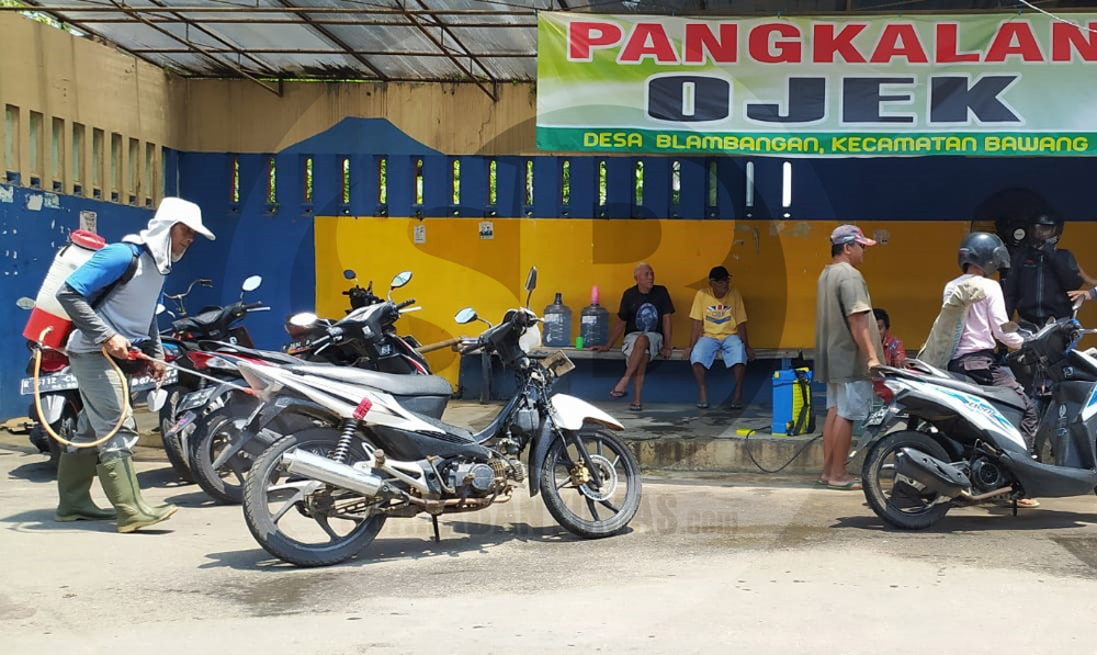 MENYEMPROT DISINFEKTAN: Warga menyemprot disinfektan ke sepeda motor dan pengendaranya yang akan masuk ke Desa Blambangan Kecamatan Bawang untuk mengantisipasi penyebaran virus korona.(SM/Castro Suwito-60)