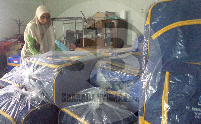 KOPER JEMAAH : Pegawai di biro perjalanan umrah Purwokerto menunjukkan koper yang akan digunakan para jemaah umrah.  (SM/Puji Purwanto)