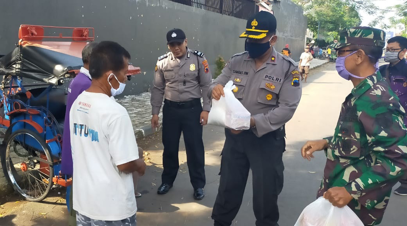 SERAHKAN SEMBAKO : Kapolsek Purwokerto Utara Kompol Sambas Budi menyerahkan paket sembako kepada seorang penerima, Rabu (13/5) lalu. (SM/dok)