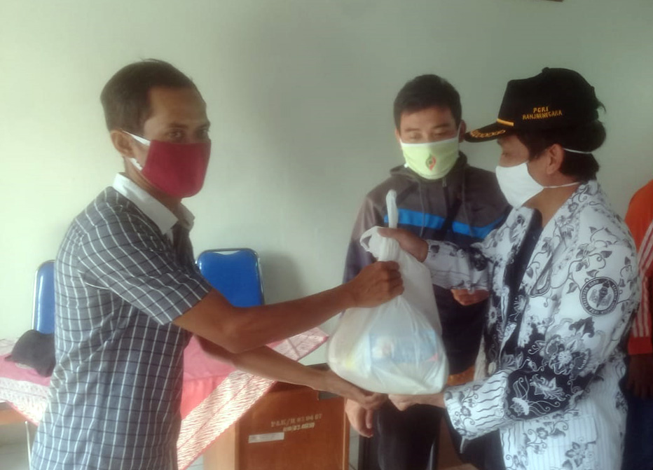 BERIKAN BANTUAN: Ketua PGRI Banjarnegara Noor Tamami memberikan bantuan paket kebutuhan pokok kepada tenaga guru honorer dan penjaga sekolah untuk meringankan beban selama pandemi korona. (SM/dok)