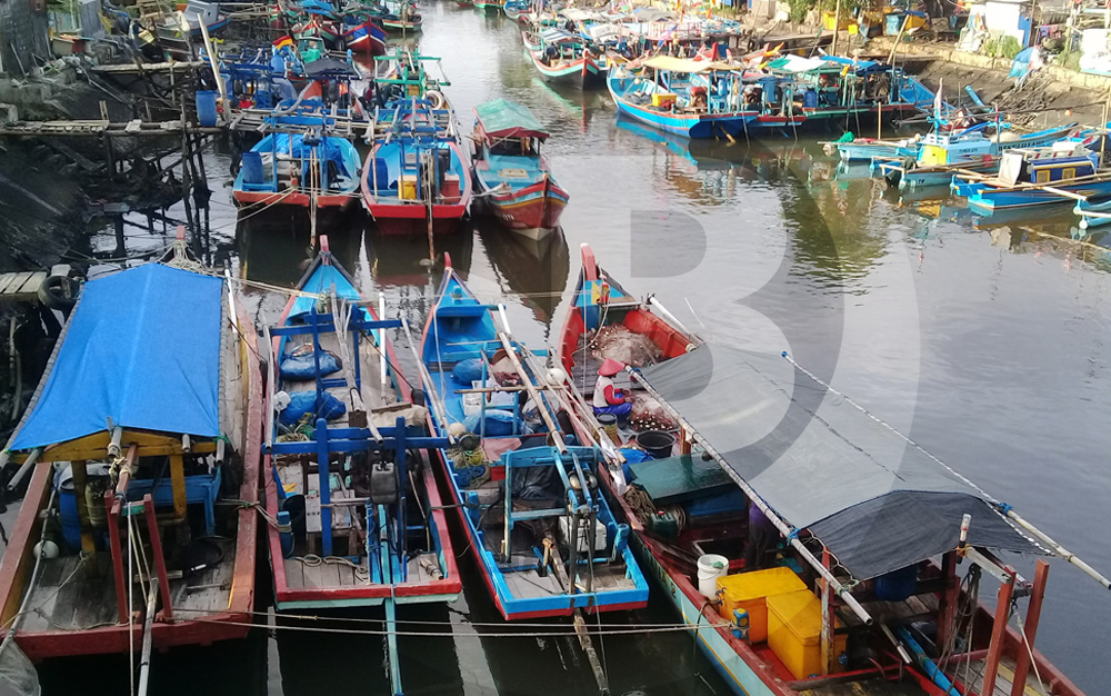 MEMBENAHI JARING: Sejumlah nelayan di Cilacap membenahi jaring di atas perahu yang disandarkan di dekat pantai, Minggu (7/6). (SB/Teguh Hidayat Akbar-2)