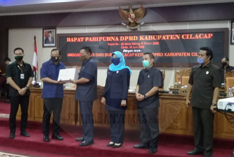 SERAHKAN RAPERDA: Bupati Tatto Suwarto Pamuji menyerahkan draf Raperda tentang Pertanggungjawaban Pelaksanaan Anggaran Pendapatan dan Belanja Daerah Kabupaten Cilacap Tahun Anggaran 2019 kepada Pimpinan DPRD, Kamis (18/6). (SB/Teguh Hidayat Akbar)