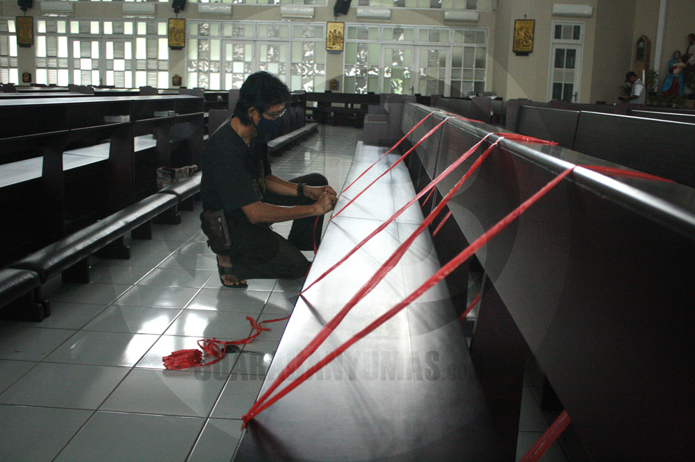 PASANG TANDA: Pengurus gereja memasang tanda dengan tali pada bangku untuk mengatur jarak antar umat di Gereja Katolik Santo Yoseph Purwokerto, Minggu (7/6). (SM/Nugroho PS-2)