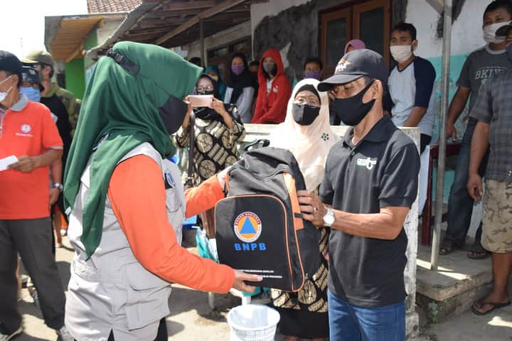 SERAHKAN BANTUAN: Koordinator Bunda Rumah Tangga Siaga Bencana Kabupaten Banyunas, Erna Husein menyerahkan bantuan sosial kepada korban kebakaran di Pancurawis Kelurahan Purwokerto Kidul Kecamatan Purwokerto Selatan, Minggu (26/7).