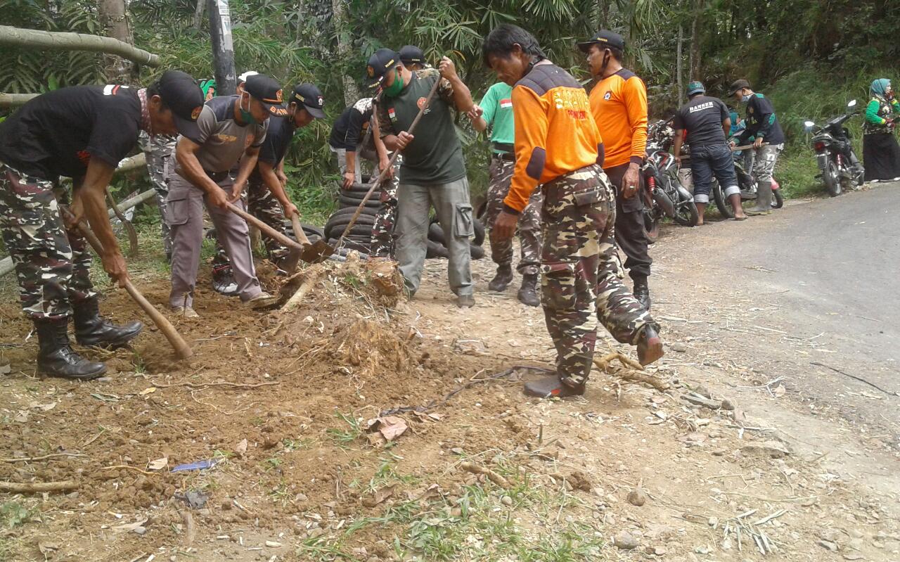 BERSIHKAN JALAN: Personel Ansor Banser Pekuncen membersihkan jalur kabupaten Cikawung-Petahunan, Kecamatan Pekuncen kemarin.