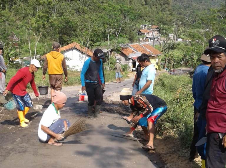 KERJA BAKTI: Warga dan personel Ansor Banser Desa Krajan, Kecamatan Pekuncen memperbaiki jalan di perbatasan Brebes-Banyumas Jumat (7/8) pagi.