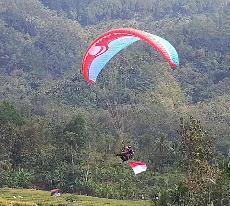 MENDARAT: Atlet paralayang yang mengibarkan bendera merah putih mendarat di Lapangan Desa Cibangkong Kecamatan Pekuncen kemarin.